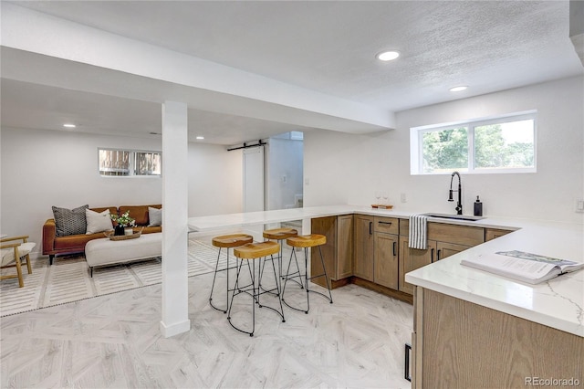 4818 Bryant St, Denver, CO 80221 - kitchen with a barn door, a peninsula, a kitchen bar, light stone countertops, and recessed lighting