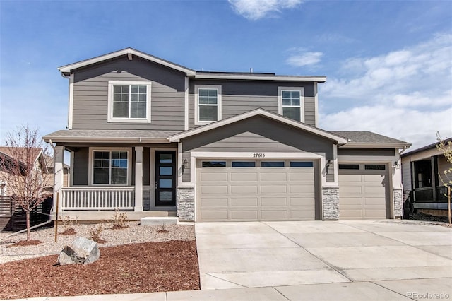 craftsman-style home featuring stone siding, covered porch, a garage, and driveway
