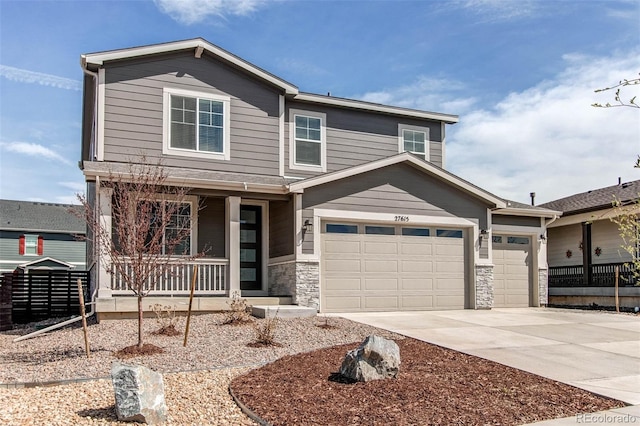 view of front facade with concrete driveway, a porch, stone siding, and a garage