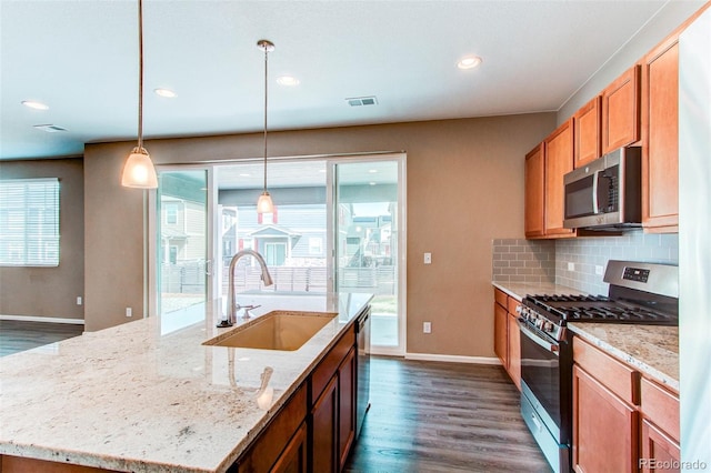 kitchen featuring dark wood finished floors, visible vents, appliances with stainless steel finishes, a sink, and backsplash