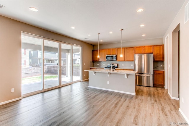 kitchen featuring an island with sink, light wood-type flooring, recessed lighting, a sink, and stainless steel appliances
