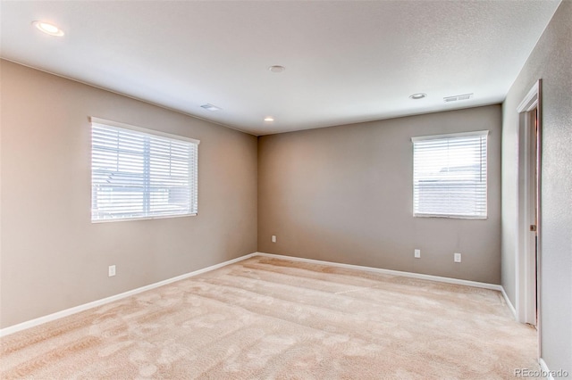 spare room featuring light colored carpet, baseboards, visible vents, and recessed lighting