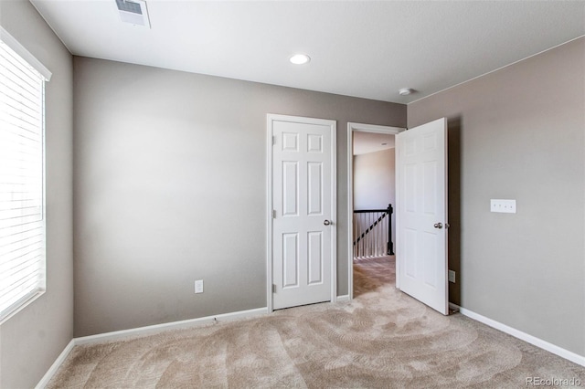 unfurnished bedroom featuring visible vents, multiple windows, and carpet flooring