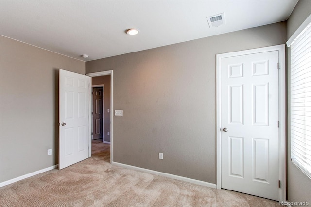 unfurnished bedroom with light carpet, visible vents, and baseboards