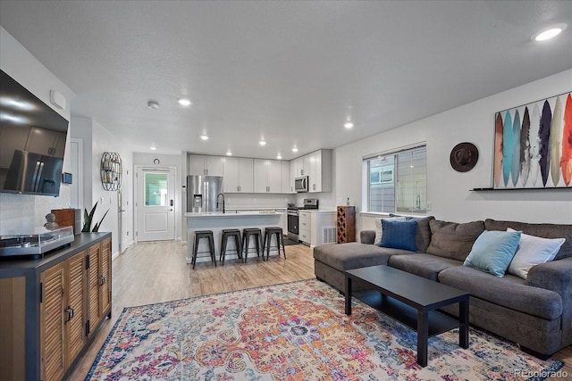 living room with light wood-style flooring and recessed lighting