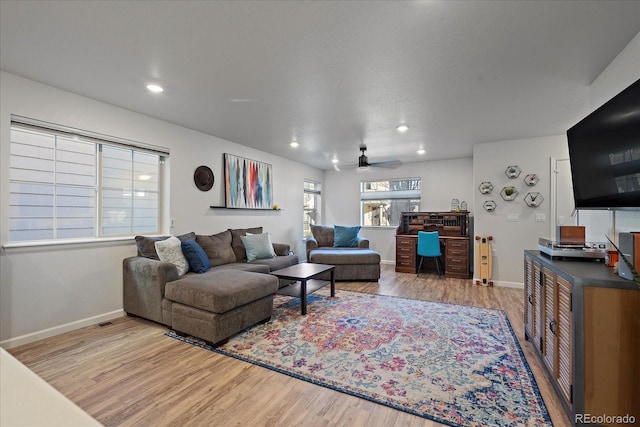 living room featuring a ceiling fan, light wood-style flooring, and baseboards