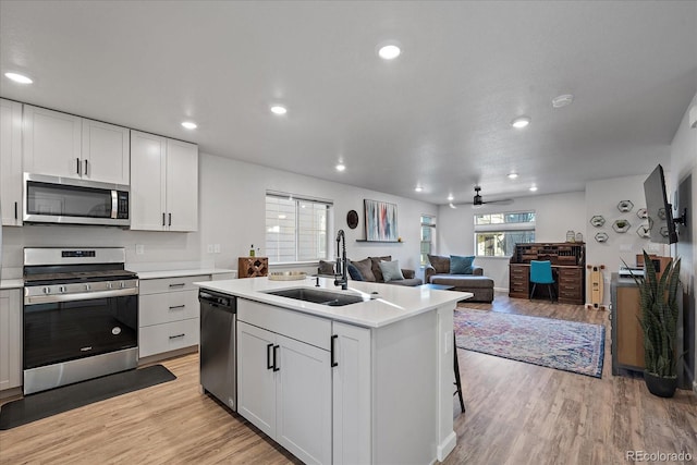 kitchen with appliances with stainless steel finishes, light wood-style floors, light countertops, and a sink