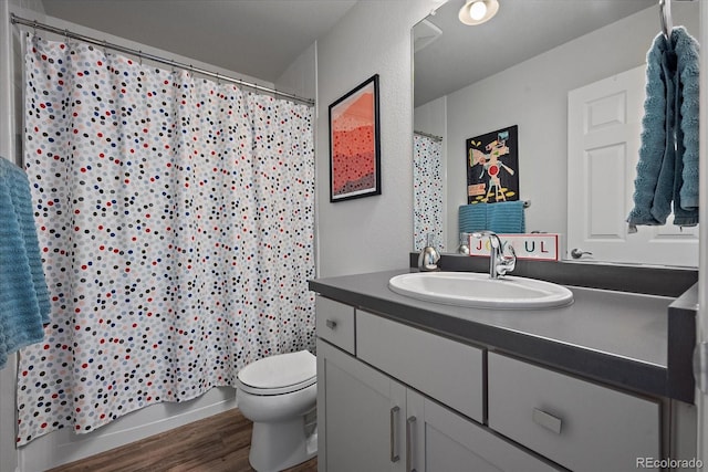 bathroom featuring shower / bathtub combination with curtain, vanity, toilet, and wood finished floors