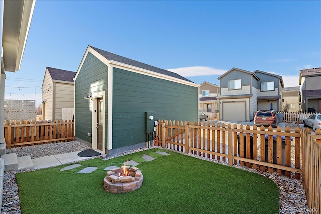 view of yard featuring a fenced backyard, a fire pit, and an outbuilding