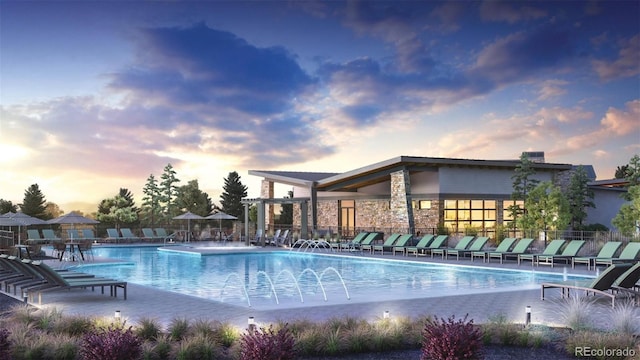 pool at dusk featuring a patio area and pool water feature