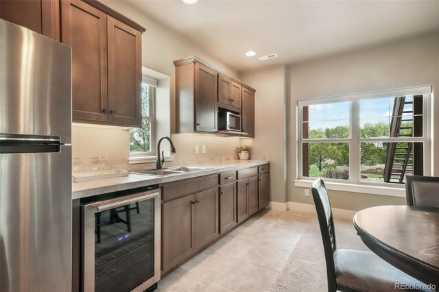17275 Gwilym Ct, Monument, CO 80132 - kitchen featuring stainless steel appliances, beverage cooler, a sink, light tile patterned floors, and light countertops