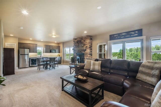 17275 Gwilym Ct, Monument, CO 80132 - living room featuring a stone fireplace, light carpet, wine cooler, recessed lighting, and baseboards