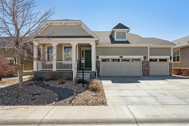 craftsman inspired home with covered porch, a garage, driveway, stone siding, and roof with shingles