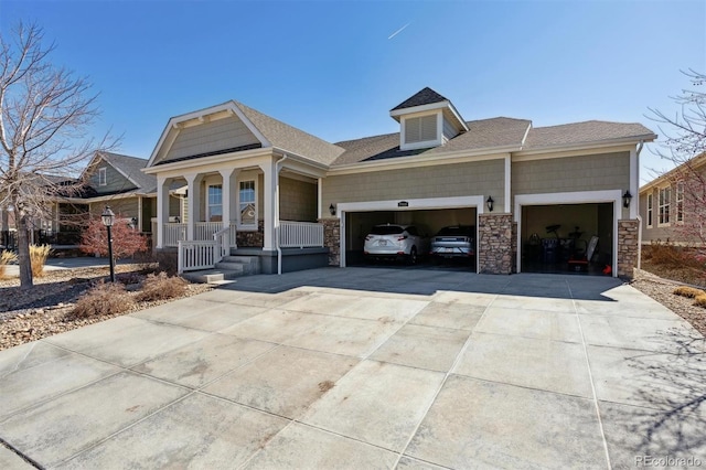 view of front facade with roof with shingles, covered porch, concrete driveway, an attached garage, and stone siding