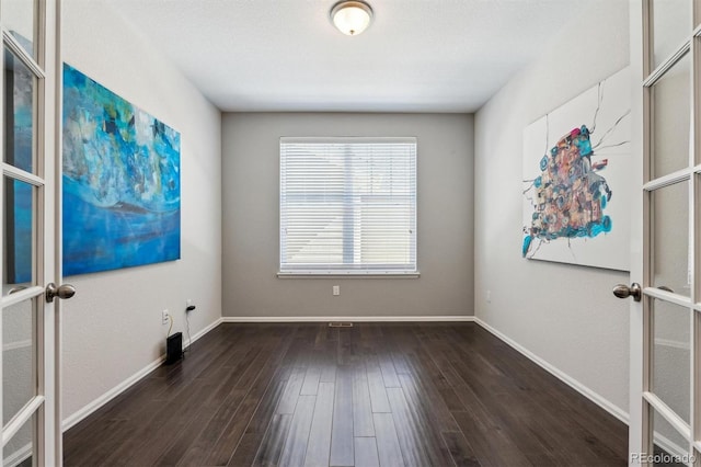 spare room featuring french doors, baseboards, and wood finished floors