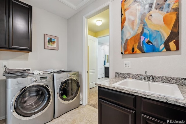 clothes washing area with cabinet space, washing machine and dryer, and a sink