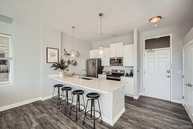 kitchen featuring white cabinetry, stainless steel appliances, decorative light fixtures, and a kitchen bar