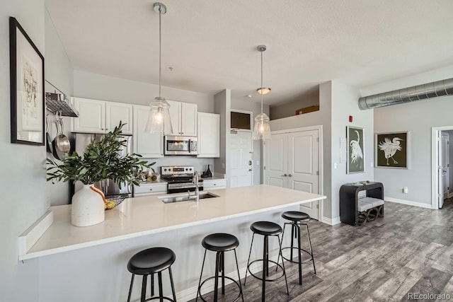 kitchen with pendant lighting, white cabinetry, a breakfast bar area, and appliances with stainless steel finishes