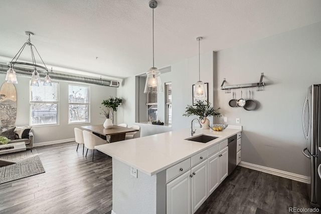 kitchen featuring sink, hanging light fixtures, kitchen peninsula, stainless steel appliances, and white cabinets