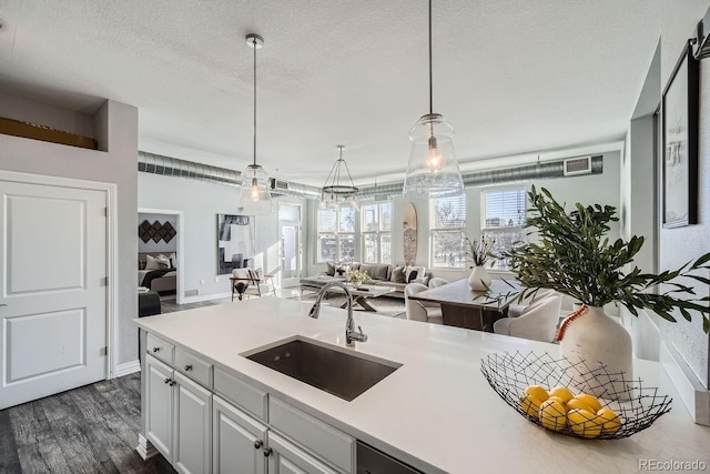 kitchen featuring sink, a textured ceiling, hanging light fixtures, dark hardwood / wood-style floors, and white cabinets