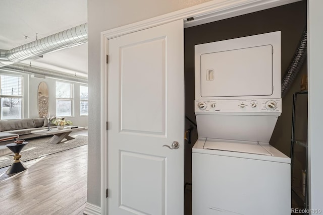 washroom with hardwood / wood-style floors and stacked washing maching and dryer