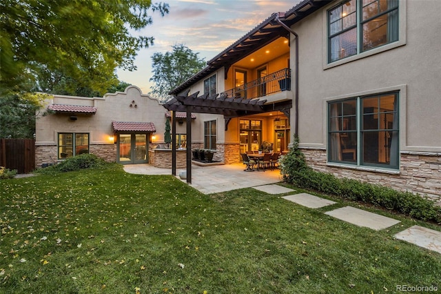 235 Eudora St, Denver, CO 80220 - back of property at dusk featuring stone siding, stucco siding, a pergola, and a balcony