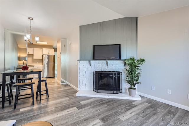 living area featuring a stone fireplace, wood finished floors, and baseboards