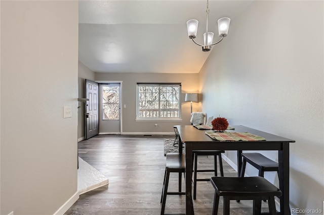 dining space with dark wood-type flooring, lofted ceiling, and a chandelier