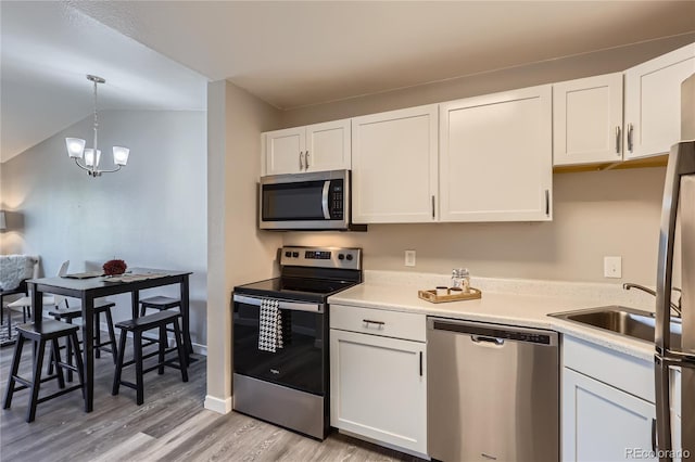 kitchen featuring white cabinetry, an inviting chandelier, stainless steel appliances, decorative light fixtures, and light wood-type flooring