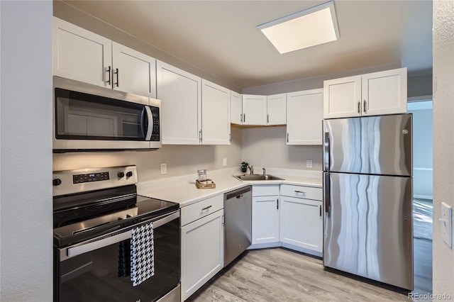 kitchen featuring white cabinetry, sink, stainless steel appliances, and light wood-type flooring