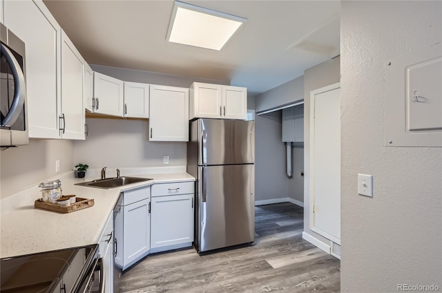 kitchen featuring appliances with stainless steel finishes, sink, light hardwood / wood-style flooring, and white cabinets