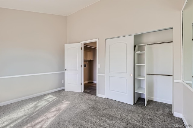 unfurnished bedroom with dark carpet and a closet