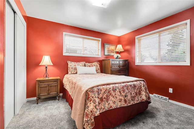 bedroom with baseboards, visible vents, light carpet, and a closet
