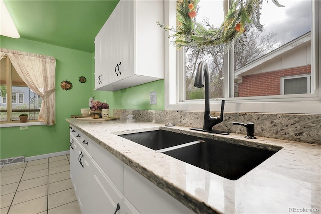 kitchen featuring plenty of natural light, visible vents, a sink, light tile patterned floors, and white cabinetry