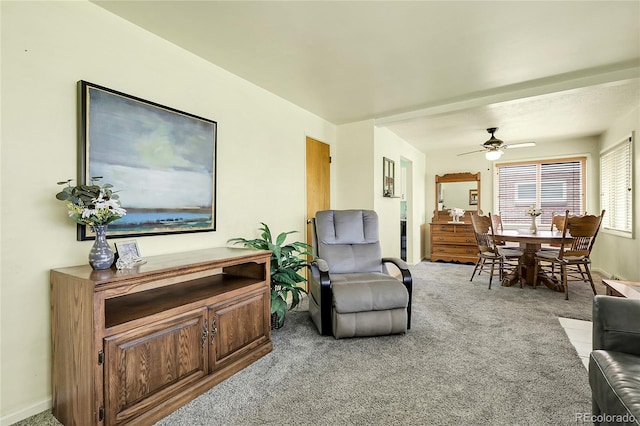 living area featuring a ceiling fan, baseboards, and light carpet