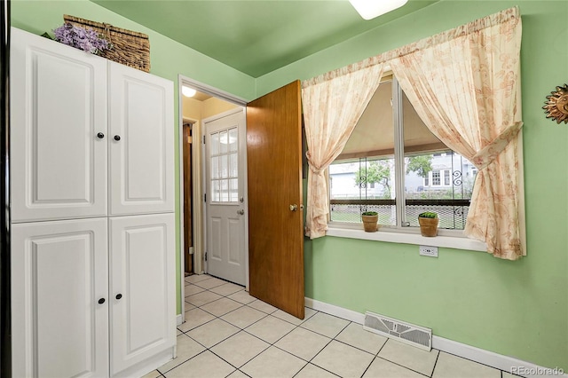 foyer featuring visible vents, baseboards, light tile patterned floors, and a wealth of natural light