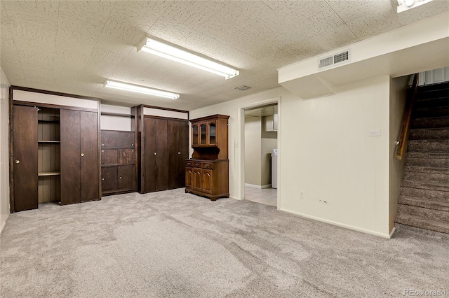 finished basement with baseboards, light colored carpet, stairs, and visible vents