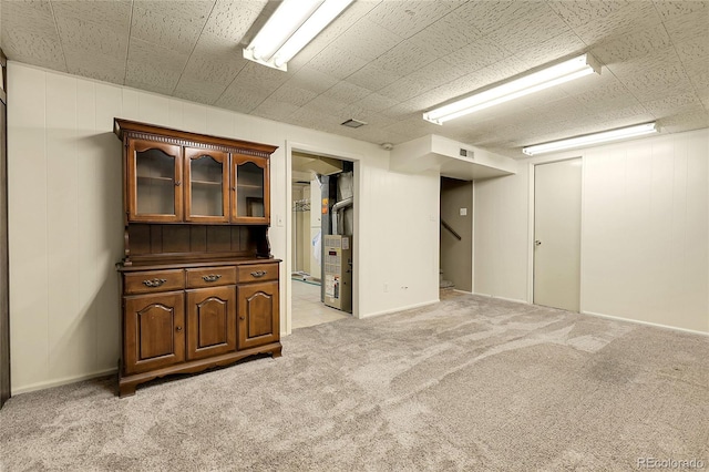 finished basement with light colored carpet, stairs, baseboards, and visible vents