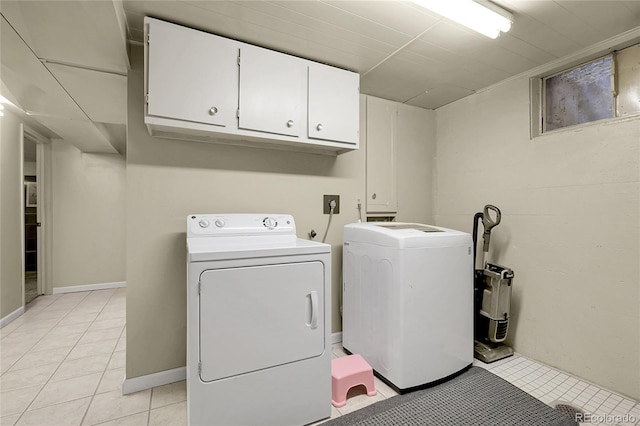 washroom featuring cabinet space, light tile patterned floors, and washer and dryer