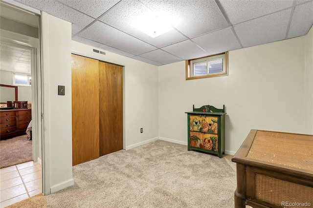 interior space with a paneled ceiling and carpet