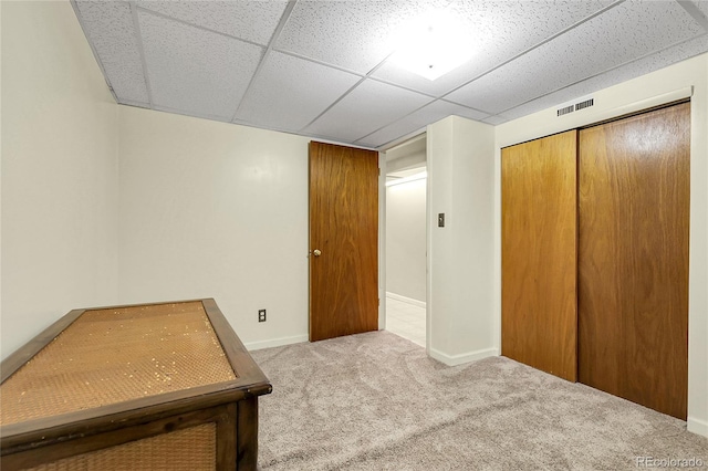 unfurnished bedroom featuring carpet flooring, a paneled ceiling, baseboards, visible vents, and a closet