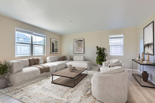 living room featuring a wealth of natural light, a textured ceiling, and light wood-type flooring