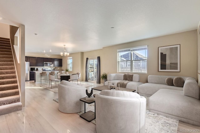 living room with a chandelier, light hardwood / wood-style flooring, and a textured ceiling