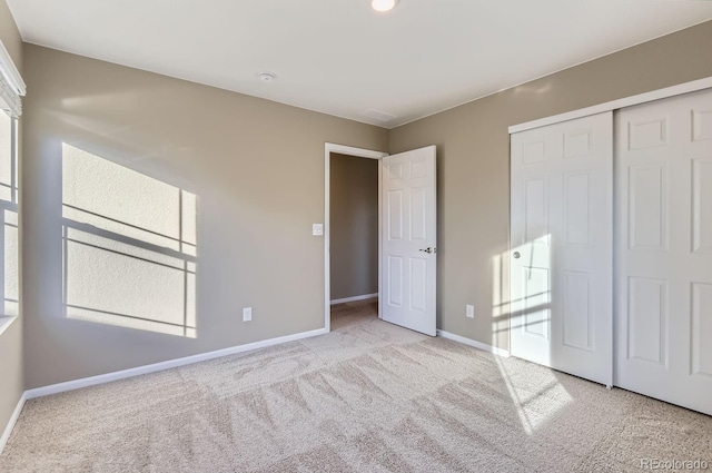 unfurnished bedroom with light colored carpet and a closet