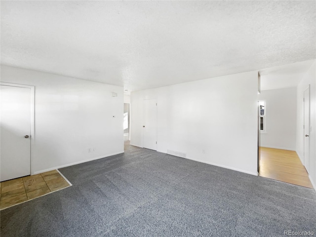 carpeted spare room featuring a textured ceiling