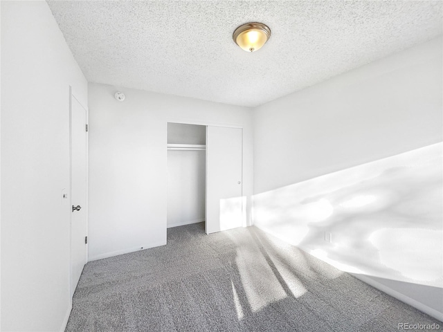 unfurnished bedroom with carpet, a textured ceiling, and a closet