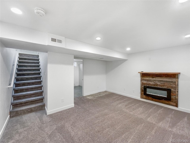 basement featuring carpet flooring and a stone fireplace