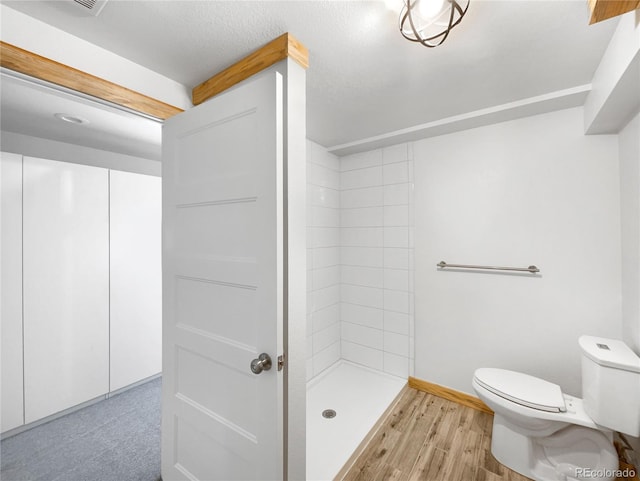 bathroom featuring hardwood / wood-style flooring, toilet, and walk in shower