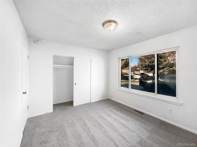 unfurnished bedroom with carpet, a textured ceiling, and a closet