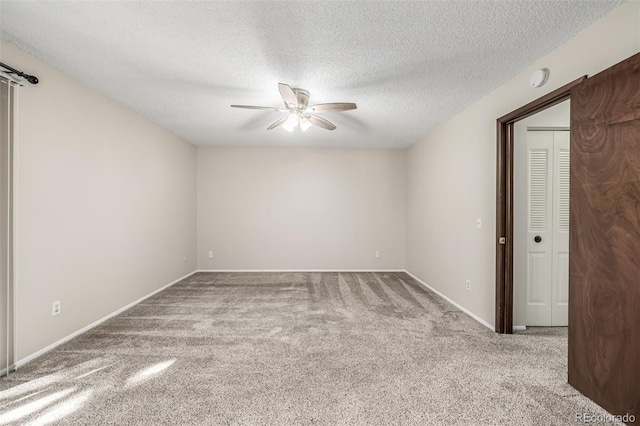 spare room with a textured ceiling, ceiling fan, and carpet